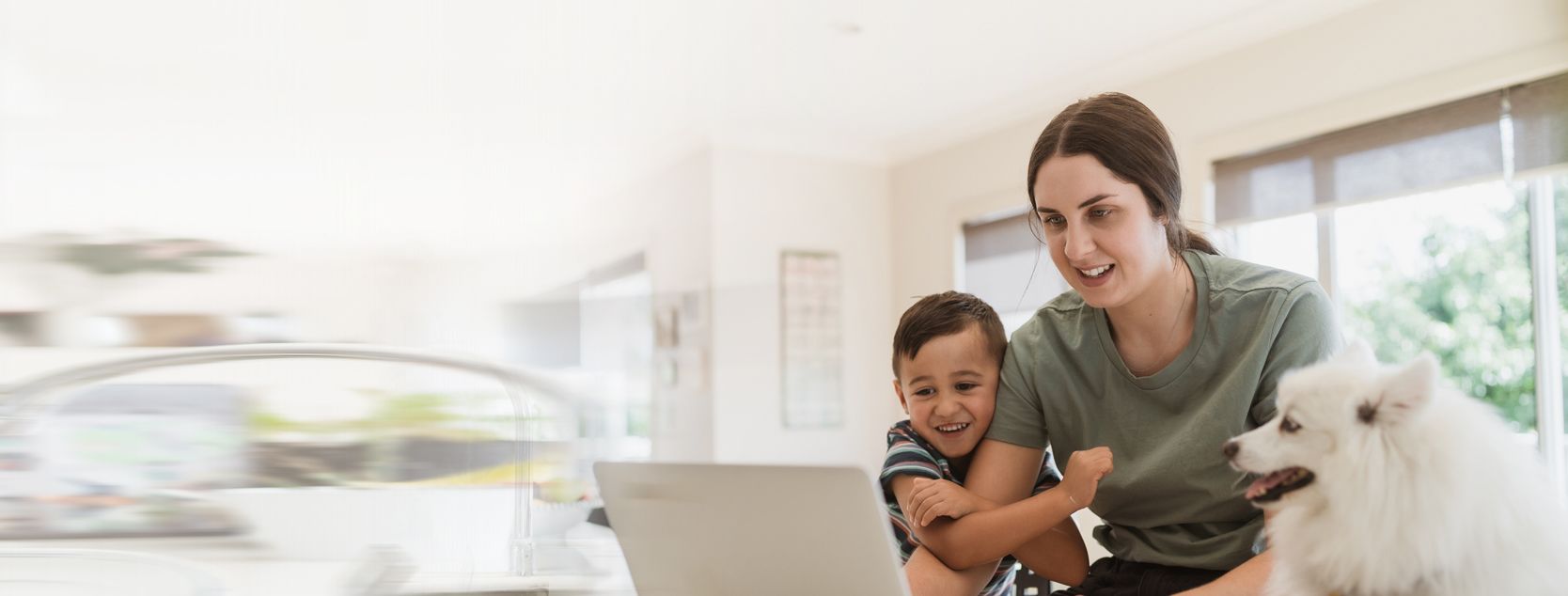 A mother, preschool boy and small dog on a video call with a laptop.