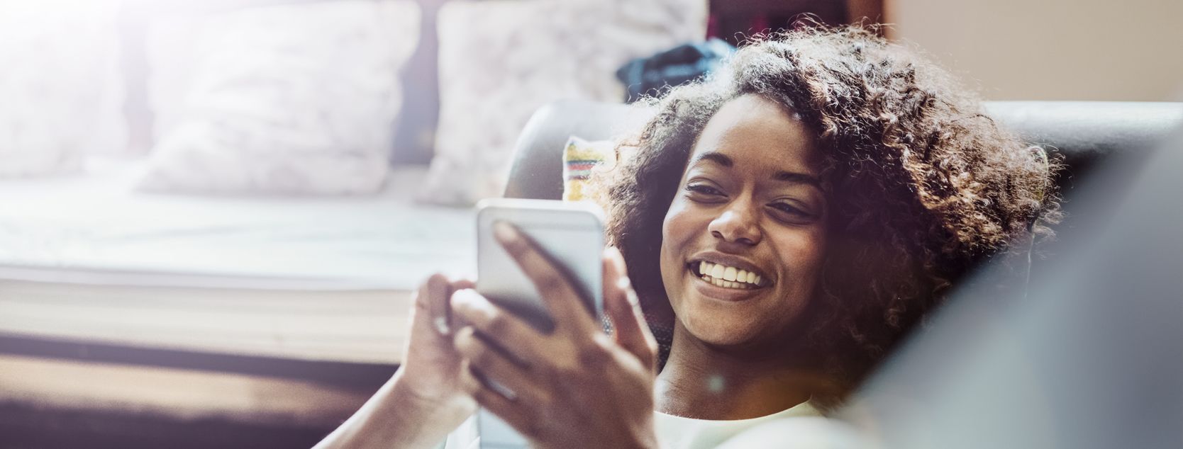 A woman lounges as she checks her Patelco account balance on her phone.