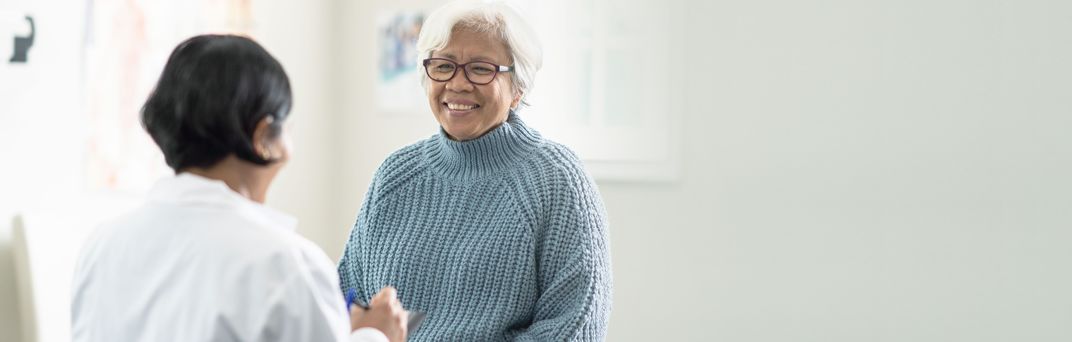 A senior citizen smiles at her doctor at a medical appointment.