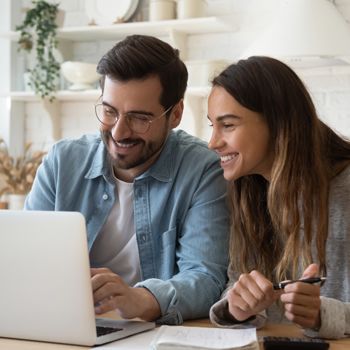 A young couple uses a laptop to check their bank accounts from Patelco Online.